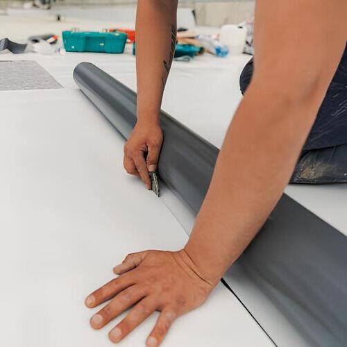 worker laying down a TPO membrane roof